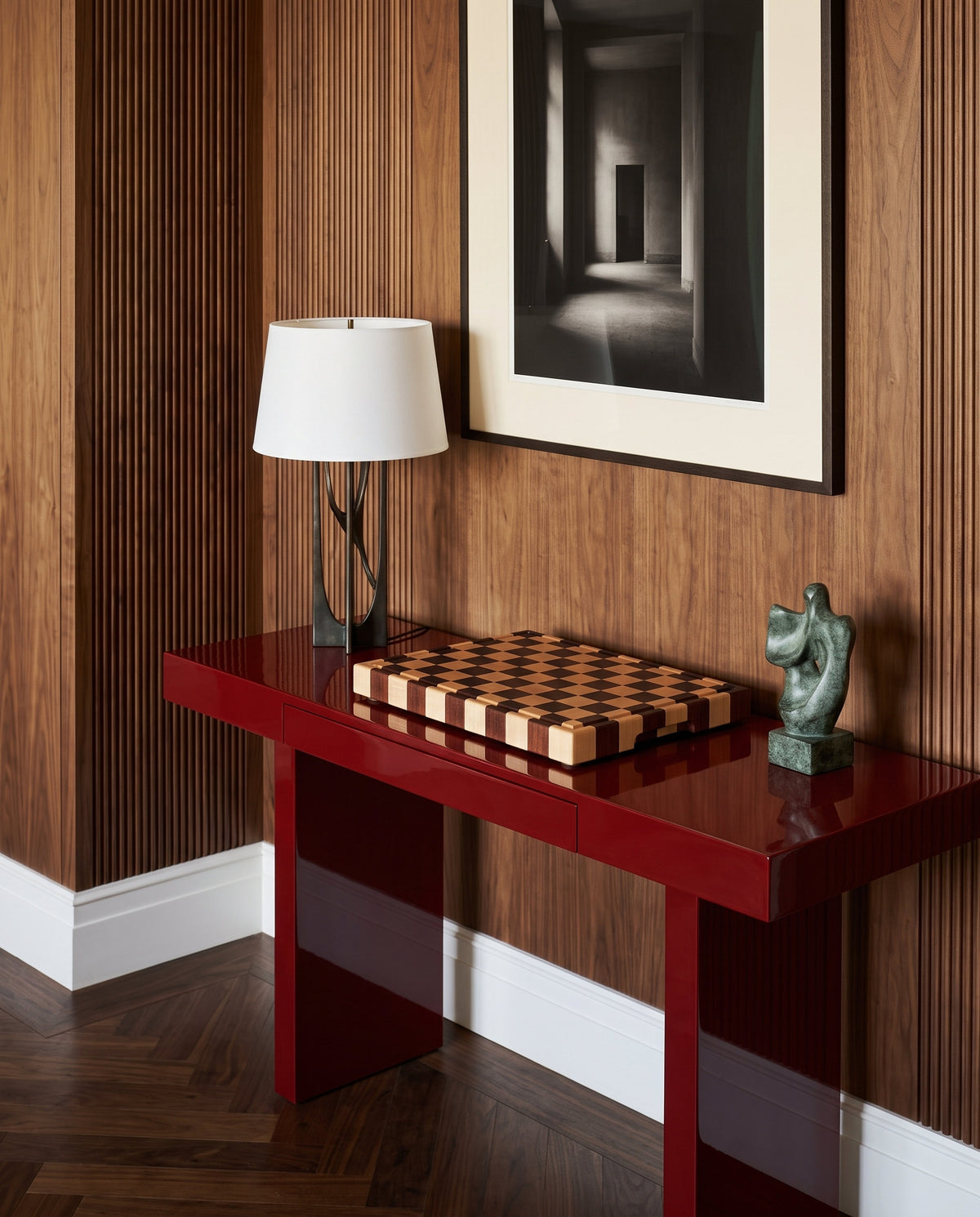 Tagliere end-grain in mogano e acero come oggetto di design su consolle laccata rossa in un ingresso boiserie