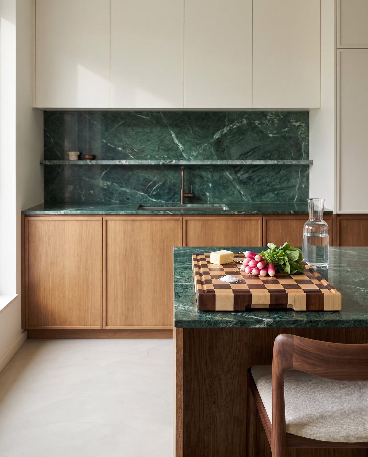 Tagliere end-grain in noce e acero con ravanelli e burro su isola in marmo verde in una cucina di design