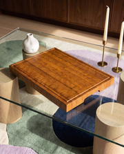 Tagliere end-grain in rovere dal design essenziale su tavolino in vetro con candele e vaso in ceramica